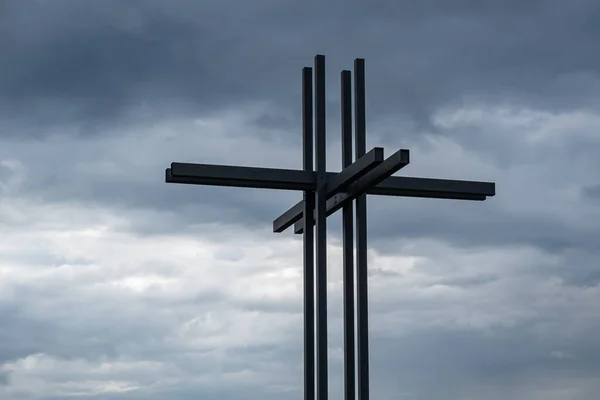 Bremgarten, Switzerland - June 13, 2020: A modern three-dimensional Christian cross with dark and storm clouds in the background