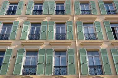 Menton, Fransa - 2 Temmuz 2020: Sıcak turuncu ve yeşil kepenkleri olan tipik bir Provencal binasının cephesi