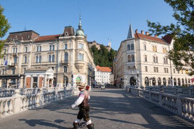 Ljubljana, Slovenya - 13 Ağustos 2020: Slovenya ulusal kostümlü bir adam Tromostovje 'deki Ljubljana' nın eski merkezinde karşıdan karşıya geçiyor