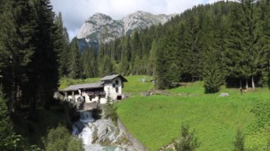 Sappada, İtalya - 9 Eylül 2020: Idyllic, İtalyan Dolomitlerinin kıyısındaki Sappada 'da terk edilmiş bir su değirmeni.