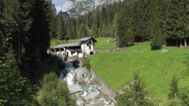 Sappada, İtalya - 9 Eylül 2020: Idyllic, İtalyan Dolomitlerinin kıyısındaki Sappada 'da terk edilmiş bir su değirmeni.