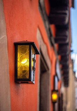 Ribeauville, Alsace, Fransa 'nın dışında canlı turuncu bir binada klasik duvar feneri.