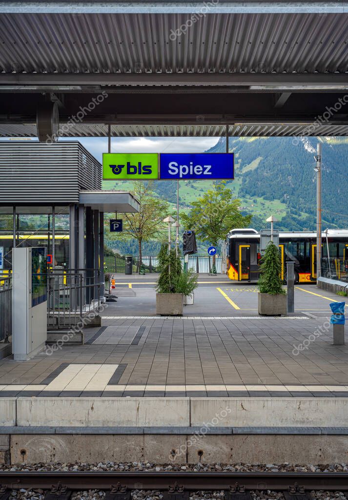 Spiez, Switzerland - September 11, 2025: Train station platform with a sign for Spiez, surrounded by mountains.
