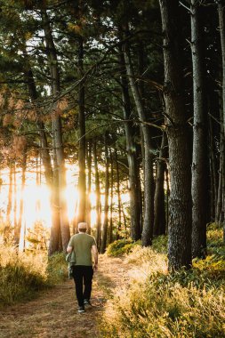Dağın tepesindeki manzarayı izleyen şapkalı bir çocuk.