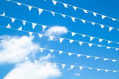 Beyaz bunting üçgen bayraklar halat çizgisinde birçok sırada asılı. Arka planda parlak mavi güneşli yaz gökyüzü. Özgürlük ya da barış kavramı. Metin için boş alanı olan kartpostal ya da takvim biçimi.