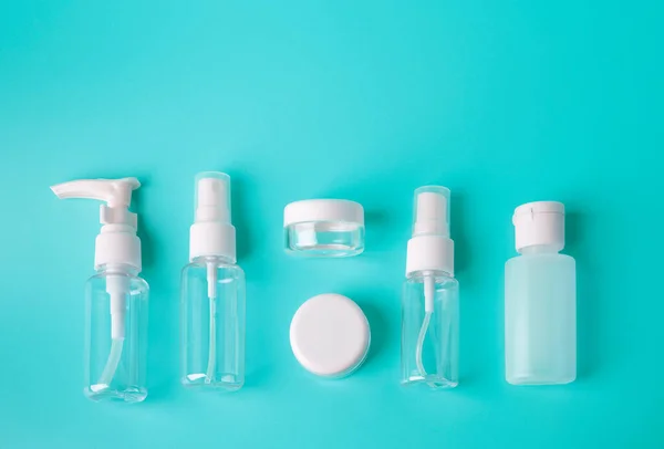 Canlı mavi arka planda bulunan altı farklı plastik şişe ya da uçuş onaylı konteynır. Kadın el bagajı ve seyahat konsepti. Metin için alanı kopyala.