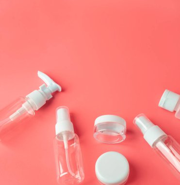 Kırmızı arka planda uçak turizmi için onaylanmış seyahat kozmetik konteynırları. İçinde bir sürü boş güzellik şişesi olan kozmetik malzemeleri. Mesaj için boş yeri olan test örnekleri. Kare biçimi