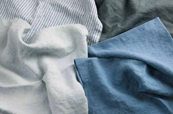 Bir yığın farklı keten kumaş. Beyaz, mavi ve gri renkli tekstil grubu. Keten ya da pamuklu kumaş. Kimseyle yakın çekim yok..