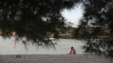 Kız ve erkek sahilde oturuyor. Erkek ve küçük kız kardeş deniz kenarında dinleniyorlar. Duygular, aşk, şefkat,