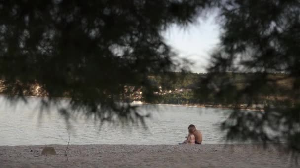Мальчик и девочка сидят на пляже. Брат и младшая сестра отдыхают у моря. эмоции, любовь, нежность, — стоковое видео