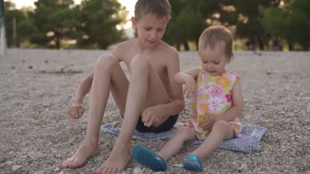 Niño y niña sentados en la playa. Hermano y hermana menor están descansando junto al mar. emociones, amor, ternura, — Vídeo de stock