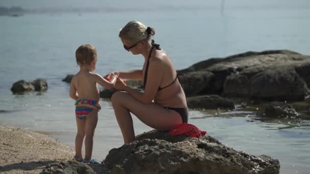 Moeder smelt haar twee jaar oude dochter met zonnebrandcrème — Stockvideo