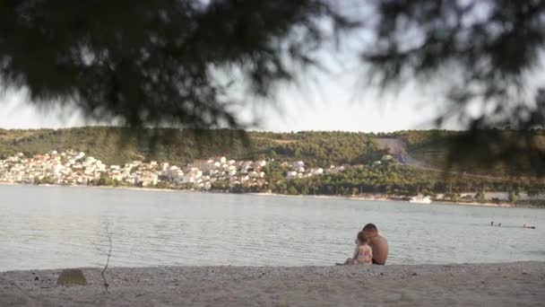 Мальчик и девочка сидят на пляже. Брат и младшая сестра отдыхают у моря. эмоции, любовь, нежность, — стоковое видео
