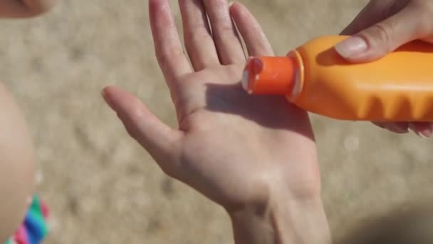 Woman squeezes sunscreen from a tube on her hand. — Stock Video