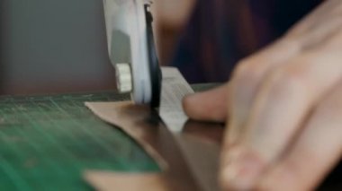 Usta, cetvelin altından seyahat çantası için bir parça deri keser. Üretim döngüsü gerçek bir deri kutusunu dolaştı. El yapımı..
