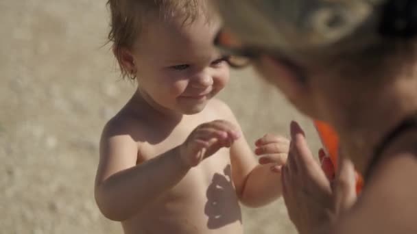 Mutter schmiert ihre zweijährige Tochter mit Sonnencreme ein — Stockvideo