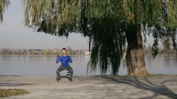 Sportovec provádí fyzická cvičení na břehu jezera. — Stock video