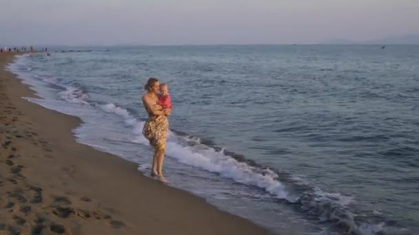 Мать гуляет со своей дочерью вдоль побережья моря. — стоковое видео
