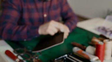 Seyahat çantası için deri zımparalayan bir zanaatkar. Üretim döngüsü gerçek bir deri kutusunu dolaştı. El yapımı..