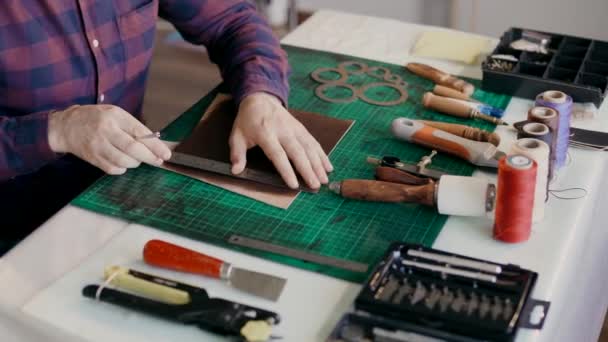 El proceso de fabricación de una maleta de viaje hecha de cuero genuino. Hecho a mano. El hombre hace marcas en el prepaquete . — Vídeos de Stock