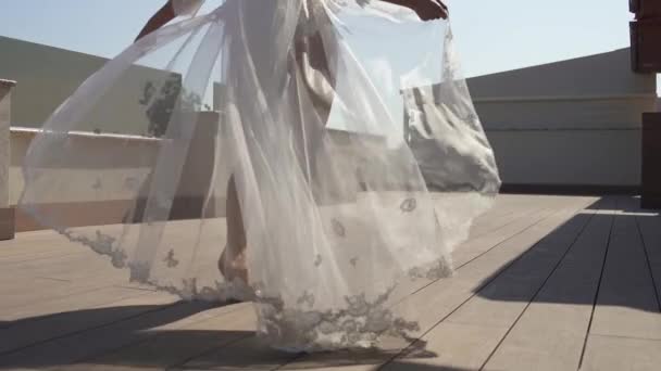Een mooie bruid in een peignoir wandelt op het terras. Meisje in mooie lingerie, de wind blaast de jurk. — Stockvideo