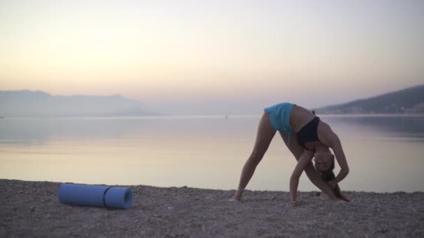 Vacker flicka som värmer upp vid havet. Sport, yoga, soluppgång. — Stockvideo