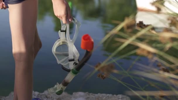 L'adolescent tient un masque avec un tube pour la natation. Le gars se tient sur un fond de lac, la mer. — Video
