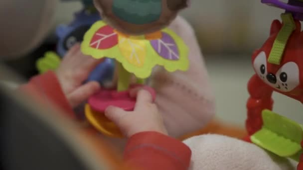 Ένα μικρό παιδί παίζει σε παιδικό κάθισμα. Κοντινό πλάνο στα χέρια του μωρού. — Αρχείο Βίντεο
