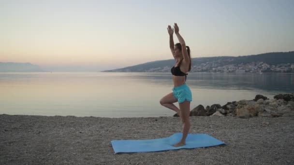 Belle fille se réchauffe et pratique le yoga au bord de la mer. Sport, yoga, plage. — Video