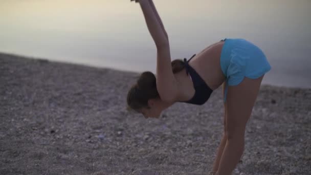 Mooi meisje doet een warming-up aan zee. Sport, yoga, zonsopgang. — Stockvideo