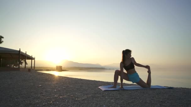 Schöne Mädchen beim Aufwärmen am Meer. Sport, Yoga, Sonnenaufgang. — Stockvideo