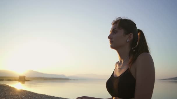 Mooi meisje doet een warming-up aan zee. Sport, yoga, zonsopgang. — Stockvideo