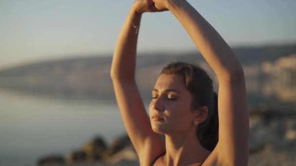 Hermosa chica se calienta y practica yoga junto al mar. Deportes, yoga, playa . — Vídeos de Stock