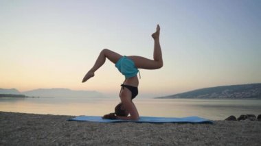Güzel kız ısınıyor ve deniz kenarında yoga yapıyor. Spor, yoga, plaj..