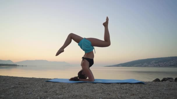 Vacker flicka värmer upp och utövar yoga vid havet. Sport, yoga, strand. — Stockvideo
