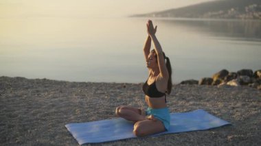 Güzel kız ısınıyor ve deniz kenarında yoga yapıyor. Spor, yoga, plaj..