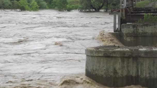 Un vecchio ponte abbandonato su un fiume che straripa. L'acqua tempestosa scorre. Estremamente alto livello dell'acqua nel fiume. Disastri naturali nell'Ucraina occidentale. — Video Stock