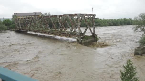 En övergiven bro över en flod som svämmar över. Stormigt vatten rinner. Extremt hög vattennivå i floden. Naturkatastrof i västra Ukraina. — Stockvideo