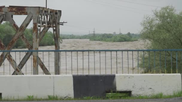 Rzeka podczas powodzi. Strumienie brudnej wody pędzą z dużą prędkością. Strzelanie odbywa się z istniejącego mostu. Katastrofy naturalne Ukraina — Wideo stockowe