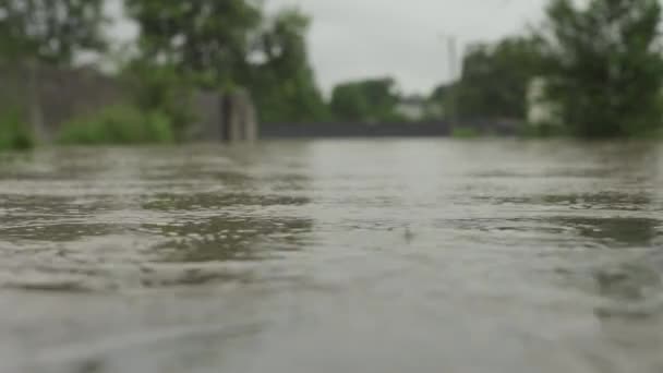 Overstroomde straat tijdens overstromingen. De camera is gelijk met het water. Water overstroomde de weg en de omheining van een privéhuis. Het regent en het waterpeil stijgt. Limnitsa rivier Oekraïne. — Stockvideo