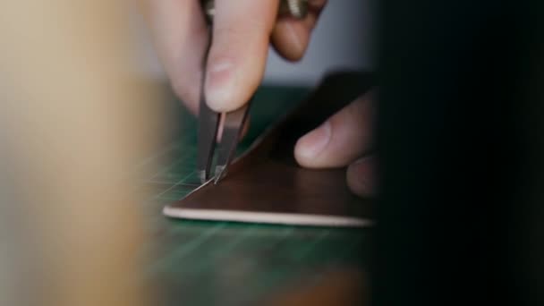 O assistente faz marcações na peça de trabalho. O processo de fabricação de uma caixa de viagem feita de couro genuíno. Feito à mão. Ver macro . — Vídeo de Stock