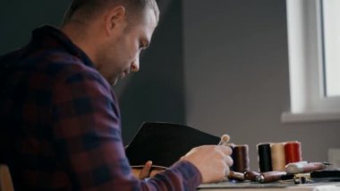 El yapımı deri cüzdan üretme işlemi. Bir insan derisine yumuşatıcı krem sürer. Her şeyin iyi yapılıp yapılmadığını titizlikle izliyor..