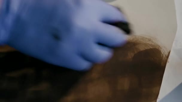 El proceso de fabricación de una cartera de cuero hecha a mano. El maestro pinta una pieza de cuero en marrón. Hecho a mano . — Vídeos de Stock