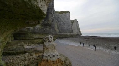 İnsanlar gelgitte çıplaklar plajını inceliyor. Etretat 'ta bulutlu bir kış günü. Fransa