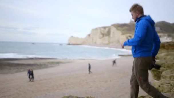 Een professionele fotograaf maakt foto 's van zijn volgende opname. Het strand van Etretat. Professionele camera. Stappen op steile rots. Ik schiet bij de hand. Etretat Frankrijk — Stockvideo