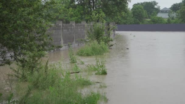 Overstroomde straat tijdens overstromingen. Water overstroomde de weg en de omheining van een privéhuis. Het regent en het waterpeil stijgt. Limnitsa rivier Oekraïne. — Stockvideo