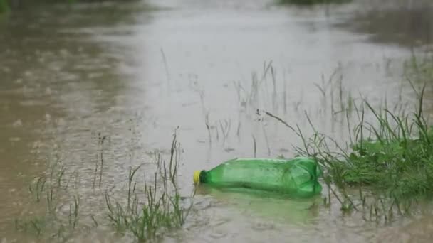 Prázdná plastová láhev uhličitých nápojů plave po vodě během povodně. Velmi špinavá voda, plastové láhve plují na vodě. Prší a hladina vody stoupá. — Stock video