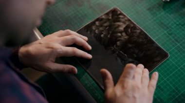 Usta cildine yumuşatıcı krem sürüyor. Gerçek deriden yapılmış bir seyahat çantası üretme süreci. El yapımı. Makro çekim.