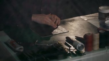 Usta cildine yumuşatıcı krem sürüyor. Gerçek deriden yapılmış bir seyahat çantası üretme süreci. El yapımı. Makro çekim.