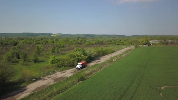 Een vuilniswagen arriveert op een natuurlijke stortplaats. Mensen dumpen afval bij de ingang. Luchtopname. — Stockvideo